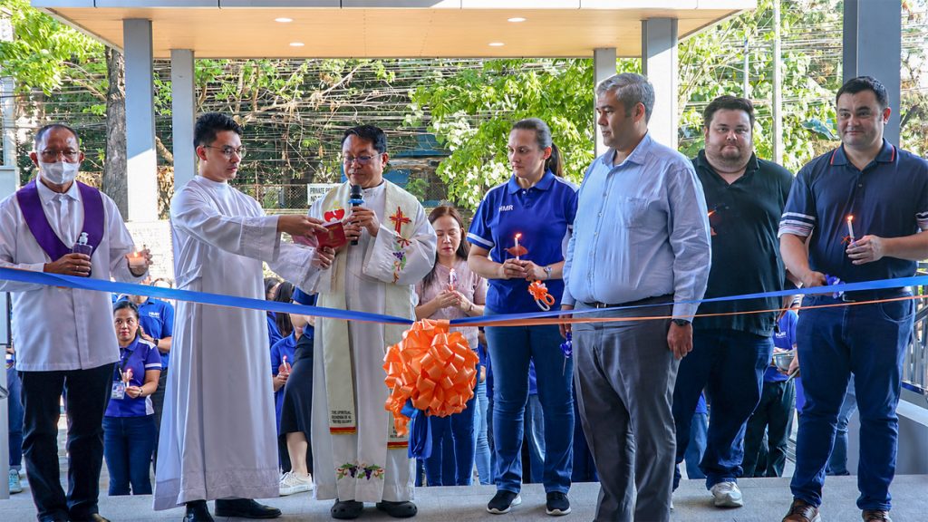 Ribbon-cutting ceremony during the opening of HMR Trading Haus Caloocan attended by company executives, guests, and clergy.